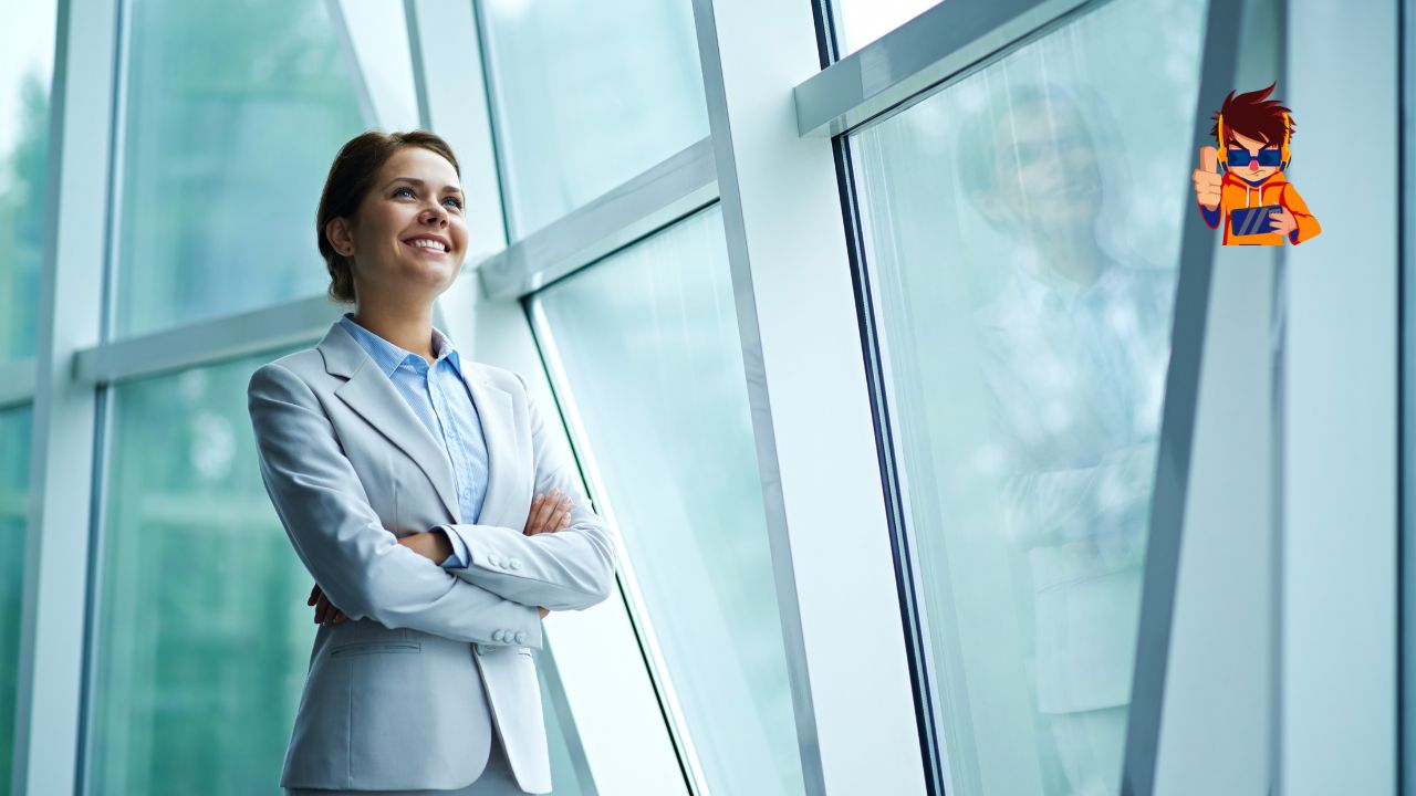 A confident businesswoman in a light gray suit stands by a large glass window with her arms crossed, smiling as she looks ahead. The modern office setting reflects her professional and optimistic demeanor.