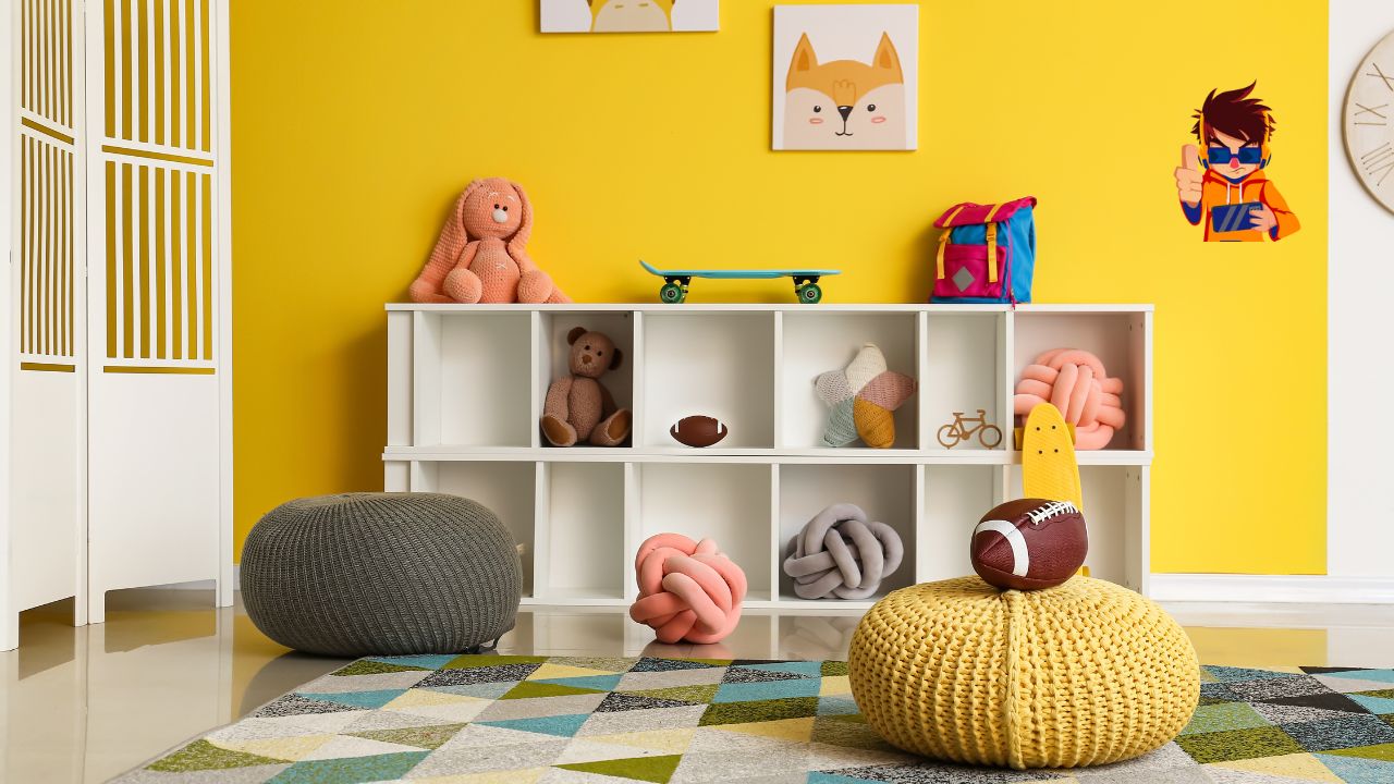 Organized in Small Spaces A colorful and neatly organized children's playroom with toys, plush cushions, and cubby storage against a bright yellow wall.